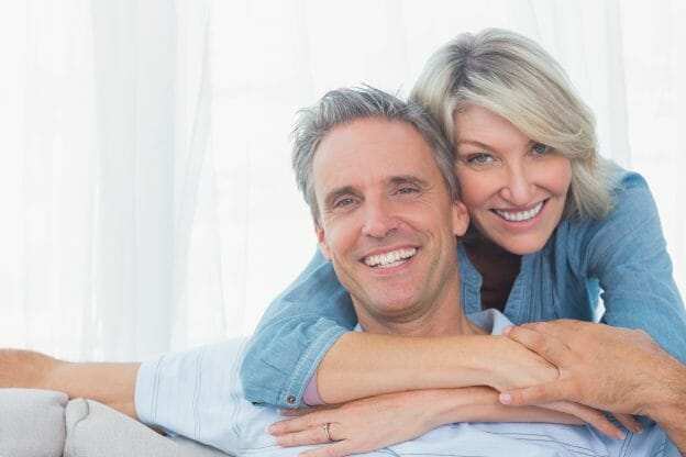 Couple smiling at the camera at home in living room